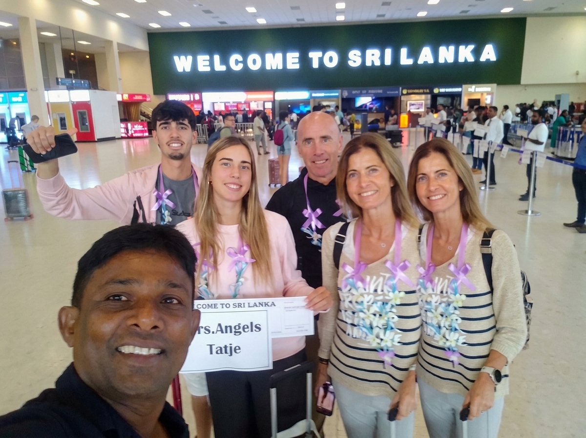 Chin welcoming a family at Colombo airport under the Welcome to Sri Lanka sign