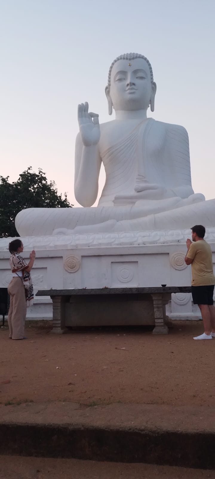 Travellers paying respect at a large white Buddha statue