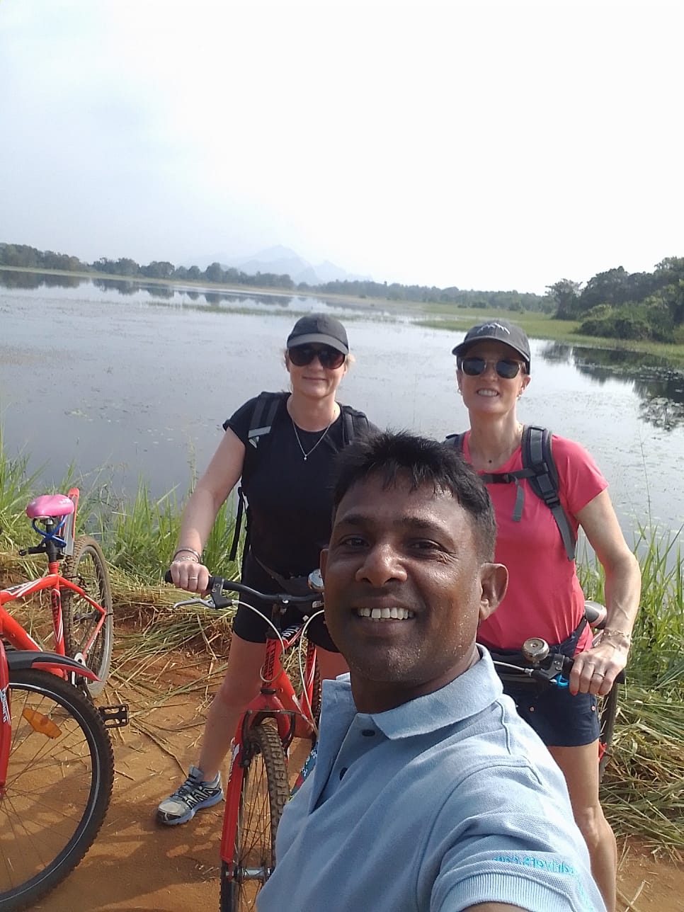 Chin with two guests on a cycling tour beside a lake near Sigiriya