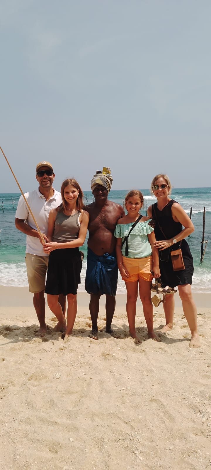Family on the beach with a stilt fisherman in Koggala