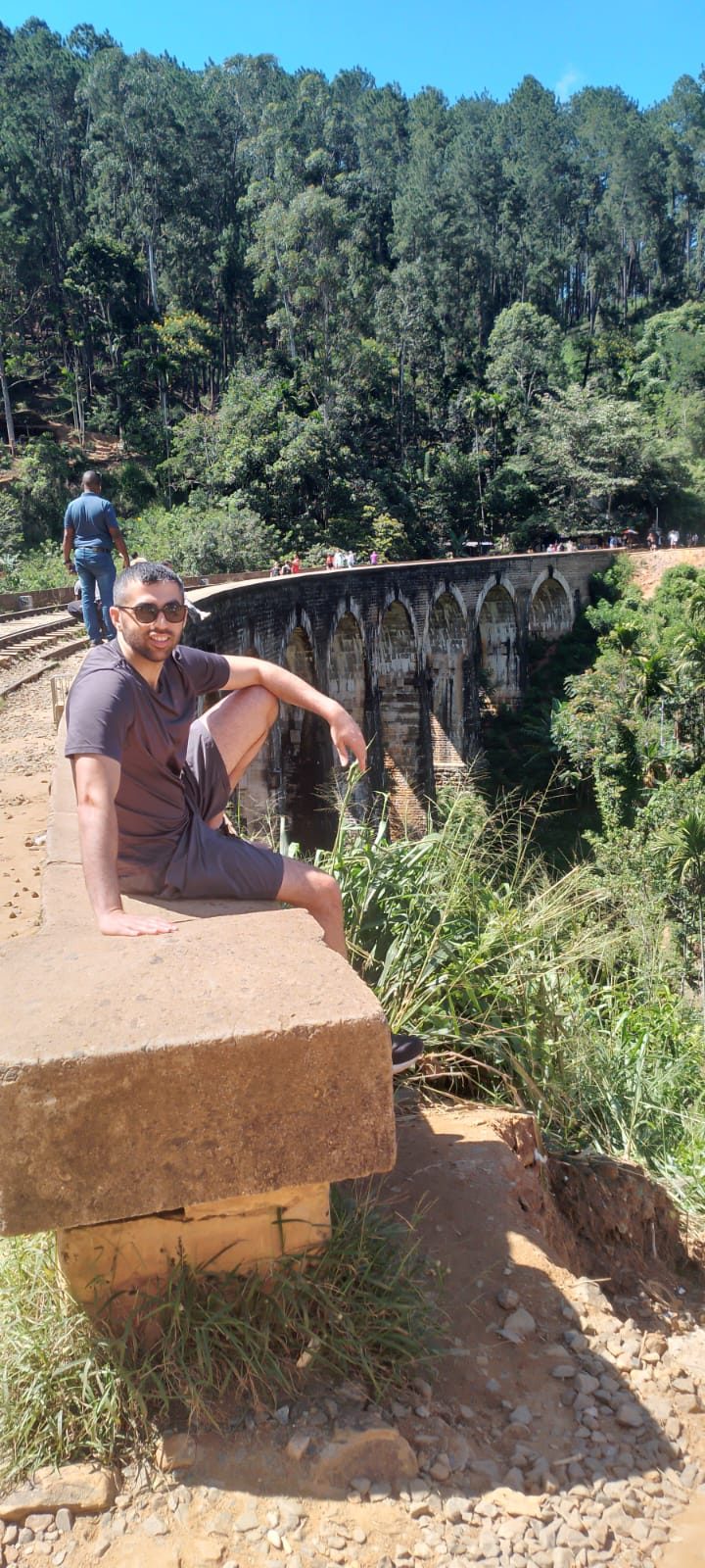 Traveller sitting on the wall of the Nine Arch Bridge in Ella