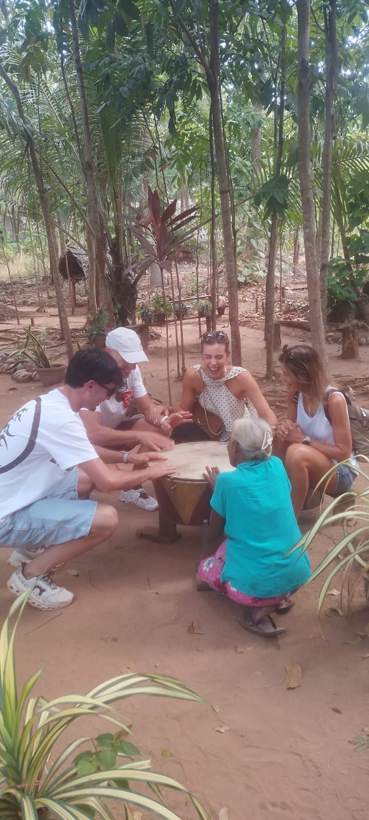 Guests playing a traditional drum with a village elder