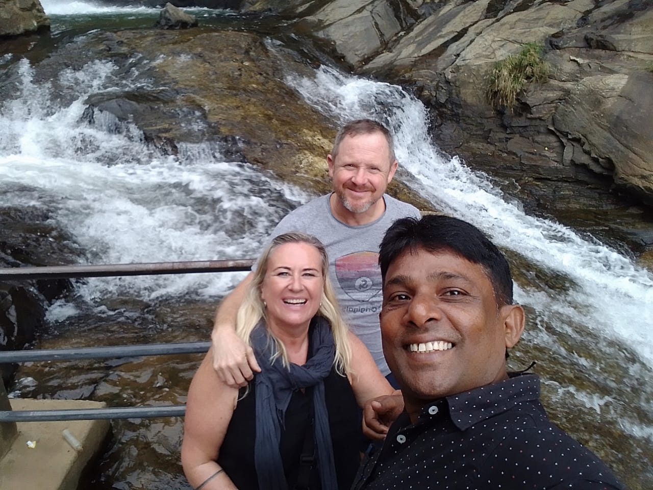 Chin taking a selfie with guests in front of a waterfall